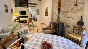 Una sala de estar acogedora con chimenea, una mesa de comedor con mantel escocés y un sofá.