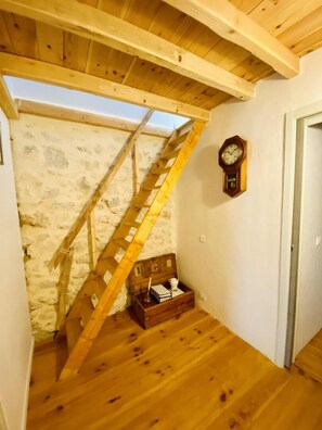 A wooden staircase leading to an attic with a stone wall, a wooden chest, and a wall-mounted clock. - Terre et Mer - ROQUEFORT DES CORBIERES (ROQUEFORT DES CORBIERES)