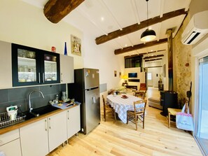 Een keuken met een houten vloer, een eethoek met een tafel en stoelen, en een groot raam.