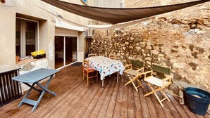 Una terraza de madera con una mesa y sillas, una hamaca y un muro de piedra.