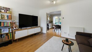Una sala de estar moderna con un televisor de pantalla plana, una estantería, una mesa de centro y un sofá.