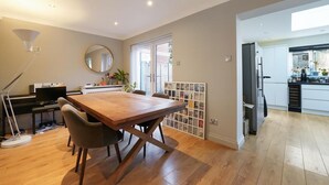 Amplia sala de estar con una mesa de comedor de madera, un piano y un espejo grande.