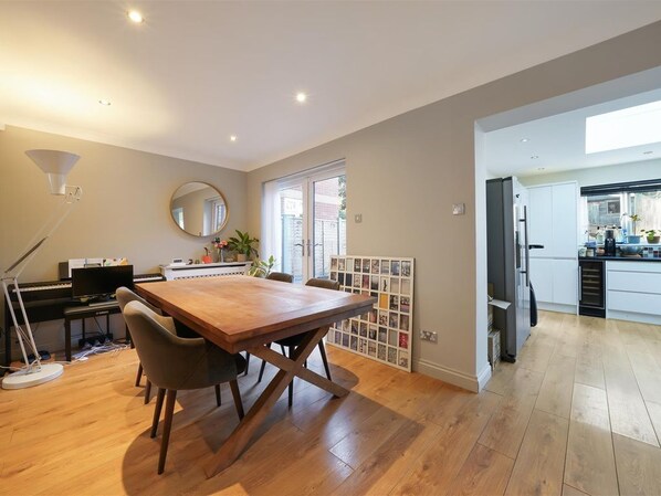 A spacious living area with a wooden dining table, a piano, and a large mirror.