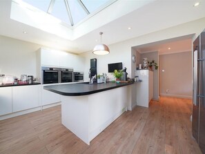 A modern kitchen with a central island, built-in appliances, and a skylight.