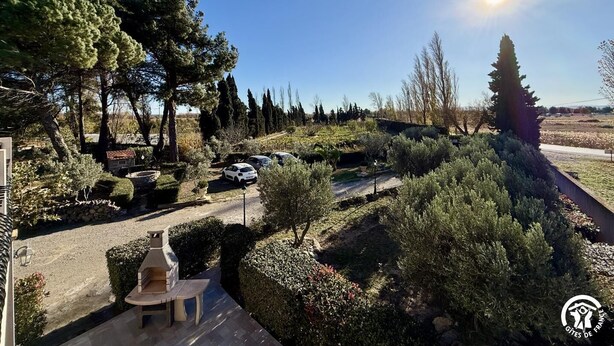 Ein Garten mit Grillplatz, parkenden Autos und blauem Himmel.