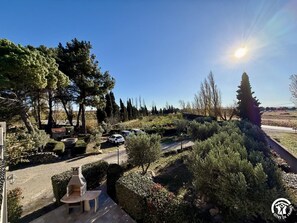 A garden with a barbecue area, parked cars, and a clear sky. - Domaine des Tamarins (NARBONNE)