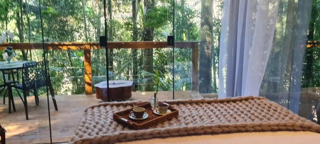 A cozy room with a large window, a wooden table, and a tray with a cup and saucer.