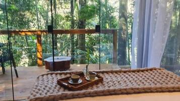 A cozy room with a large window, a wooden table, and a tray with a cup and saucer.