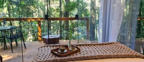 A cozy room with a large window, a wooden table, and a tray with a cup and saucer.