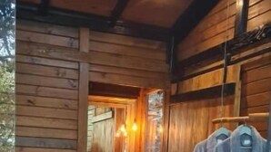 A wooden cabin interior with a bed, a mirror, and a robe rack. - Tree House (Marechal Floriano)