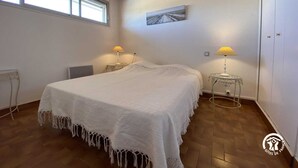 Une chambre avec un grand lit, deux lampes de chevet, un plafond en bois et une fenêtre.