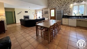 Un vaste espace de vie agrémenté d’un mur en pierre, d’une table à manger avec des chaises, d’un canapé et d’un coin cuisine équipé d’un réfrigérateur et d’un évier.