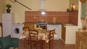 Una cucina compatta con lavatrice, un tavolo da pranzo con sedie, un lampadario e uno schienale piastrellato.