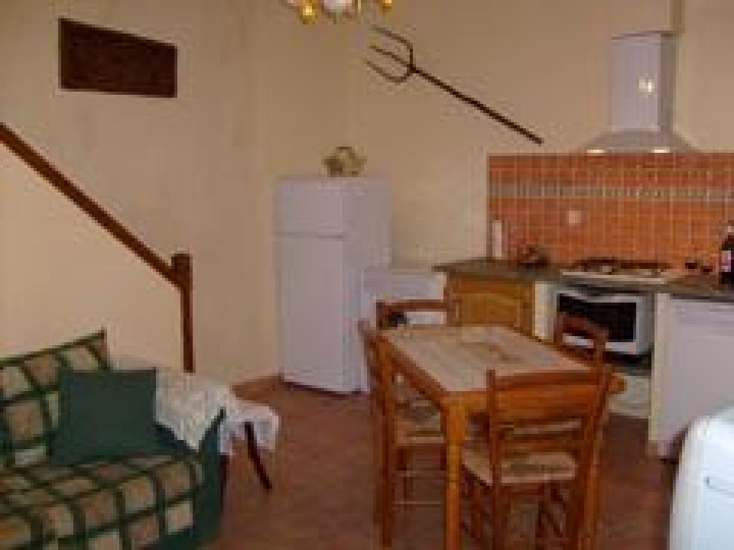 A compact living space with a kitchenette, a dining area with a table and chairs, and a sofa.