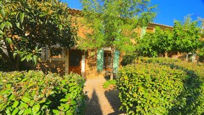 Un sentiero conduce a un edificio con facciata tradizionale, circondato da rigogliosa vegetazione.