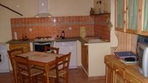 Una cucina compatta con tavolo e sedie, un piccolo forno e un frigorifero.