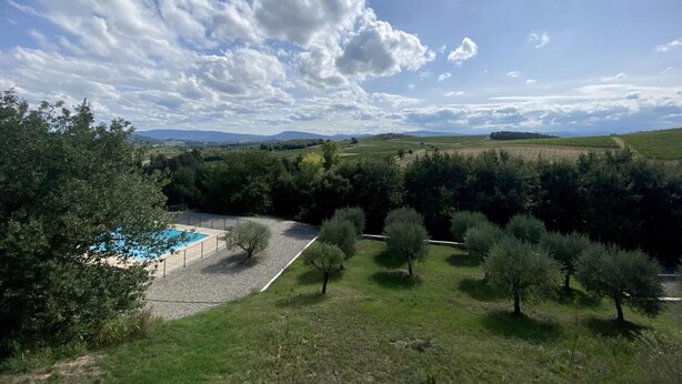 Une piscine entourée d’arbres et une pelouse, le tout sous un ciel dégagé.