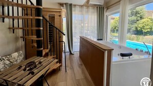 A modern interior with a wooden staircase, a pool view, and a small bar area. - Sous les Toits - Sauna & Balneotherapy (Canet D Aude)
