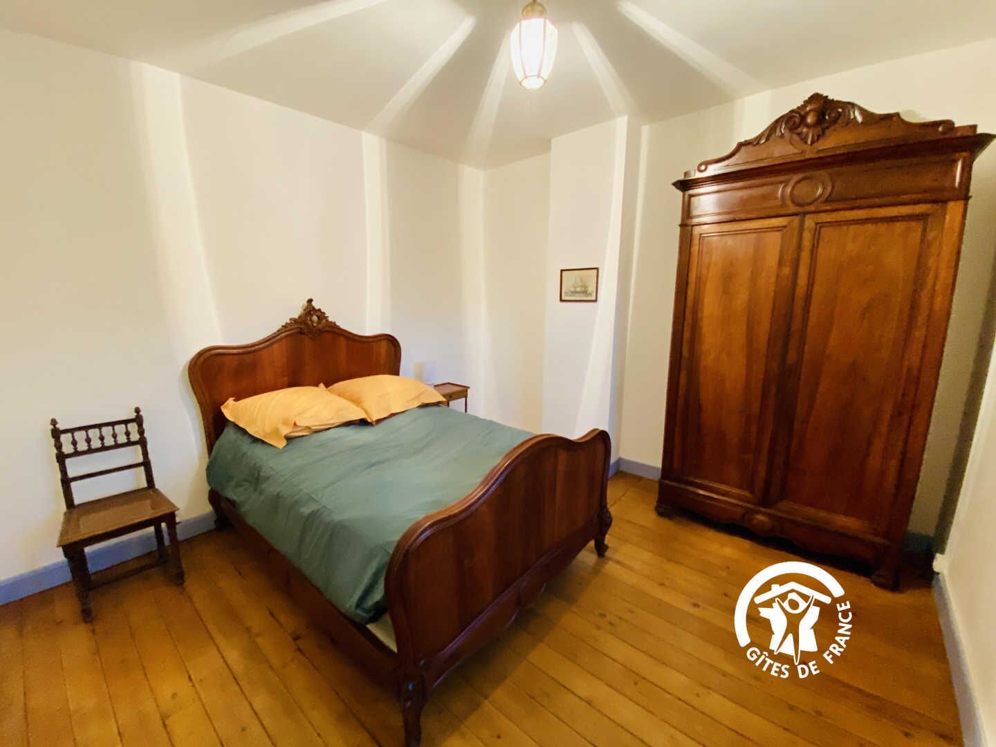 A bedroom with a wooden bed, a nightstand, a chair, and a wardrobe.