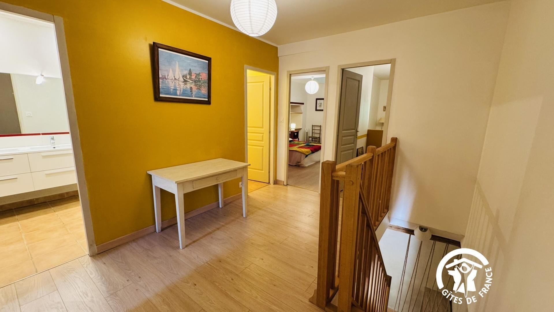 A hallway with a wooden bench, a painting on the wall, and a staircase with a wooden railing.