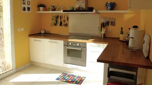 Une cuisine avec des armoires blanches, un four en acier inoxydable et un plan de travail en bois.