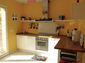 A kitchen with white cabinets, a stainless steel oven, and a wooden countertop. - Vista Alegre - FITOU (FITOU)