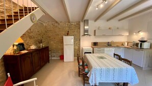 Une cuisine compacte avec un coin repas, un escalier et un mur en pierre.