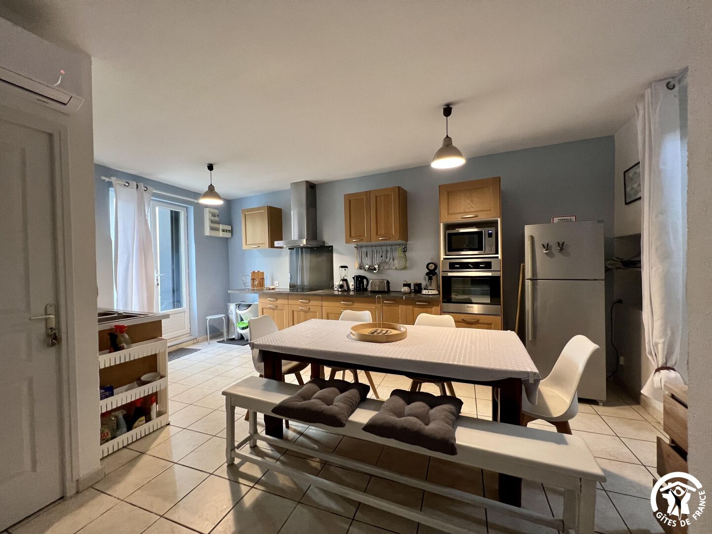 Una cocina compacta con armarios de madera, microondas integrado y refrigerador.