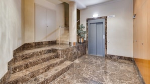 A marble staircase leading to a door labeled "BAIXOS" with a potted plant beside it.