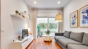 A modern living room with a grey sofa, a white entertainment unit, and a round wooden coffee table.