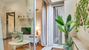 A modern interior with a glass door leading to a balcony, a small round table with a plant, and a potted plant on the balcony.