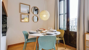 A dining area with a round table, chairs, and a hanging light fixture. - Gran Via City Center Apartment (Barcelona)