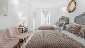 Ein Schlafzimmer mit zwei Betten, einem Nachttisch, einem Sessel und einem Spiegel an der Wand.