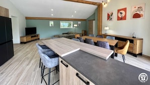 Una cocina moderna con una isla grande, taburetes de bar y un comedor con una mesa larga.