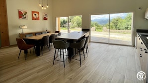 Un comedor amplio con una mesa larga y sillas, techo de madera y vistas al exterior gracias a puertas correderas grandes.