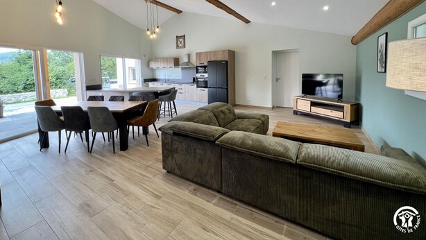 Un espacio de estar moderno con comedor, sofá, televisor y cocina.