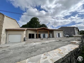 Un bâtiment à deux étages doté d’un garage, d’un porche couvert et d’un mur de soutènement en pierre.