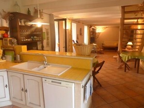 A compact kitchen with a sink, a dishwasher, and a dining area with a table and chairs.