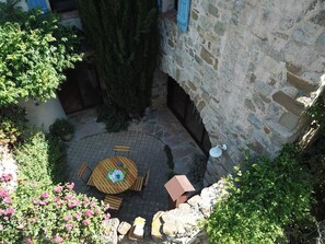 A courtyard with a round wooden table and chairs, surrounded by stone walls and potted plants. - La Capelagne - ALBAS (ALBAS)