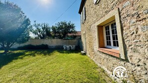 A stone house with a small porch and a grassy yard. - Etoiles des Salins - Gîte 2 (PORT LA NOUVELLE)