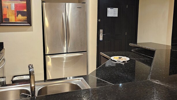 Cozinha moderna com eletrodomésticos de aço inoxidável, bancada de granito preto e porta preta.