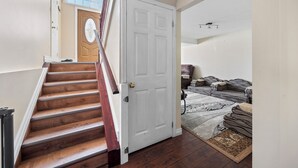 Una escalera que lleva a una habitación con una puerta blanca, suelo de madera y un tapete.