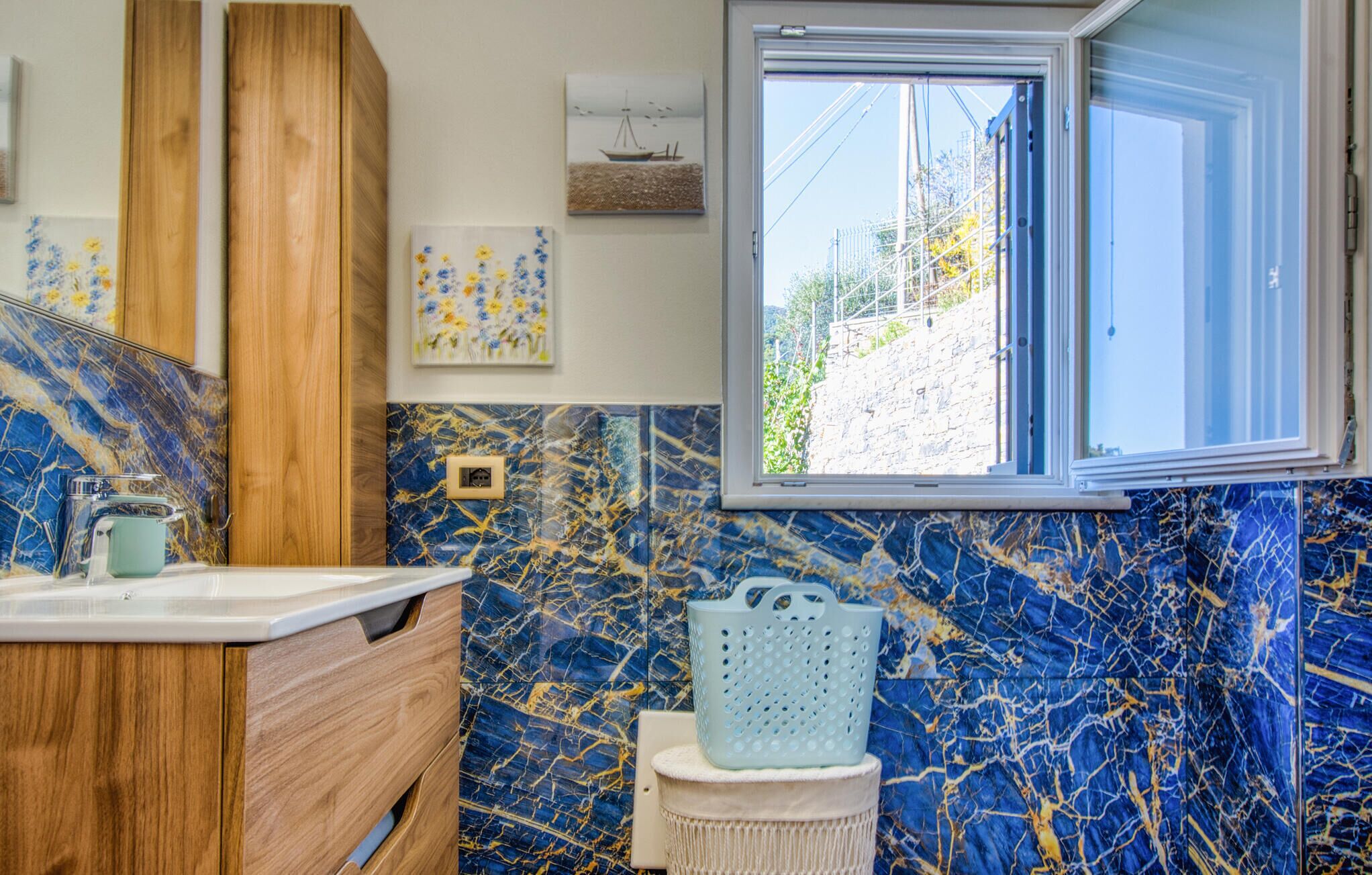 A bathroom with a marble backsplash, wooden cabinets, a window, and a cat tree.
