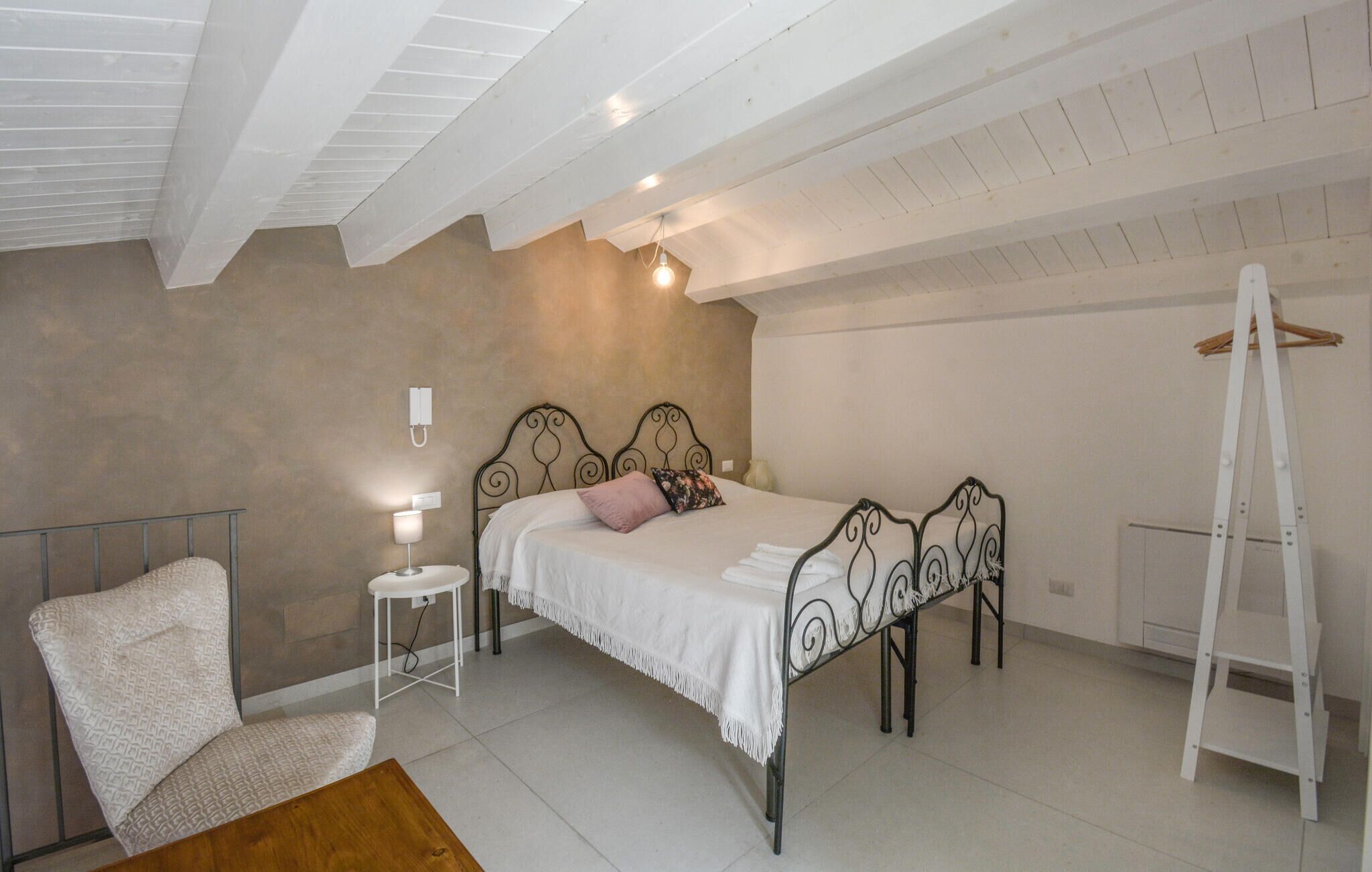 A bedroom with a bed, bedside table, chair, and a ladder.