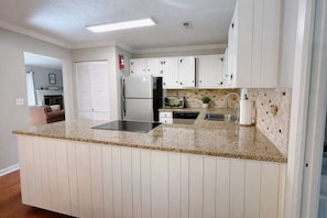 A kitchen with white cabinetry, a granite countertop, a built-in microwave, and a stainless steel refrigerator. - Relax at this 3-Bedroom Oasis With Private Deck And Hot Tub Inside Rumbling Bald (Lake Lure)