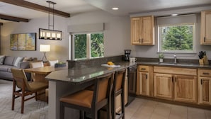 A modern kitchen with a central island, wooden cabinets, and large windows offering views of greenery. - Spacious 2BR Villa at Sheraton Lakeside Terrace Villas Near Beaver Creek Skiing (Avon)