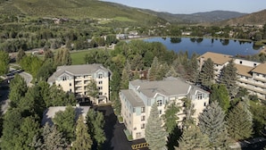 A multi-story hotel with a central courtyard, surrounded by dense forest and a lake in the background. - Spacious 2BR Villa at Sheraton Lakeside Terrace Villas Near Beaver Creek Skiing (Avon)