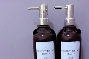 Two bottles of body wash with pumps against a purple background. - Manotemple Guesthouse (Luang Prabang)