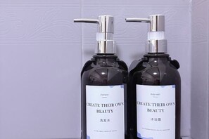 Two bottles of body wash with pumps, labeled 'CREATE THEIR OWN BEAUTY' in English and Chinese. - Manotemple Guesthouse (Luang Prabang)