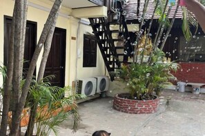 Ein Innenhof mit einem Ziegelkübel, Palmen und einer Treppe.
